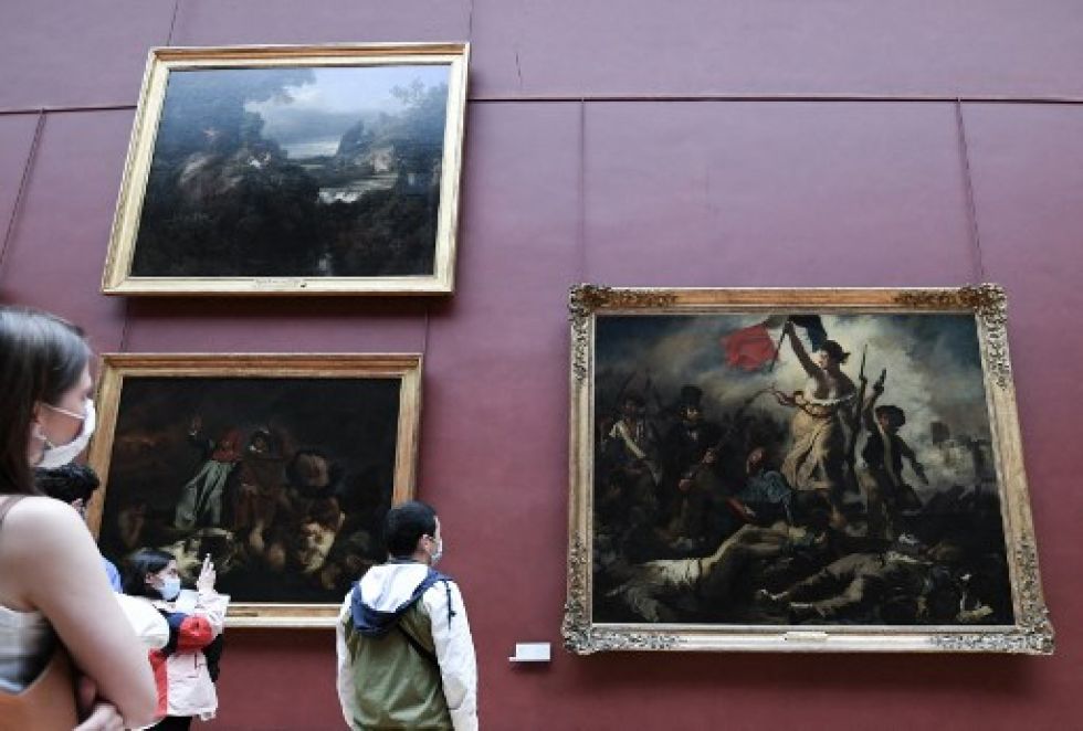 Visitantes del museo Louvre de París observan la famosa pintura "La Libertad guiando al pueblo" del artista Eugene de Lacroix. Los museos reabrieron después de varios meses.s