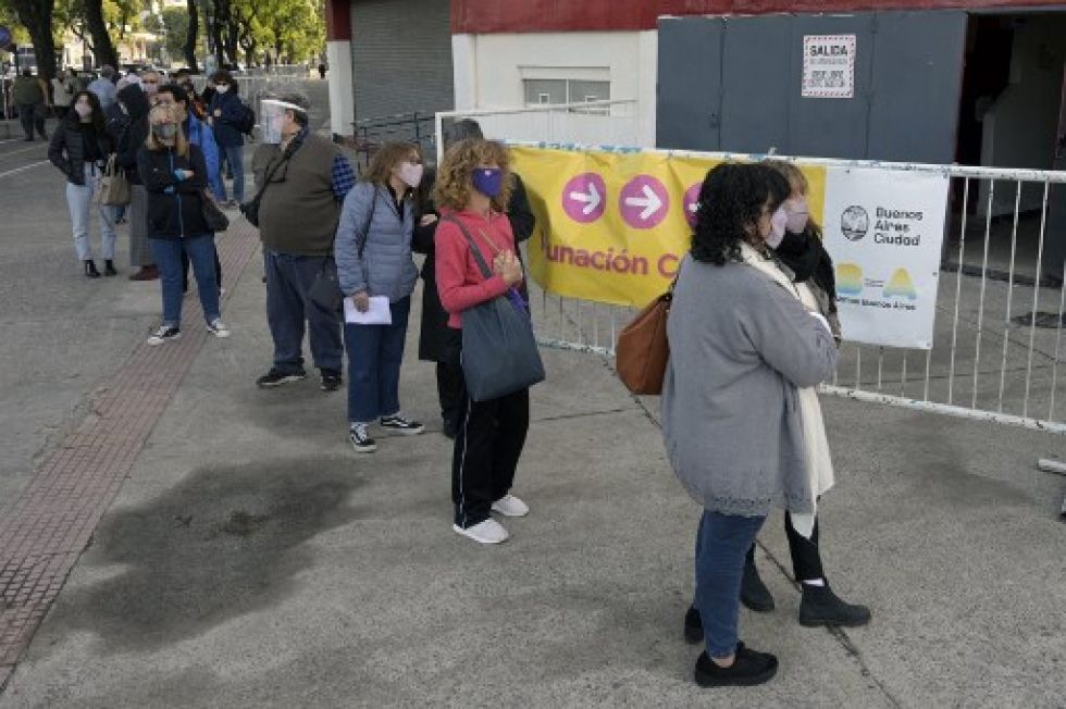 Decenas de personas hacen fila en un vacunatorio de la ciudad de Buenos Aires, en medio de una escalada de fallecidos por el covid-19.