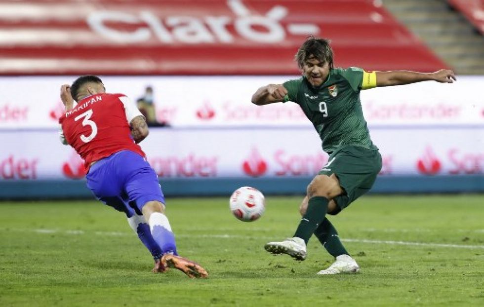 El chileno Guillermo Maripan (izq.) y el boliviano Marcelo Martins compiten por el balón durante su partido de fútbol de clasificación sudamericano.
