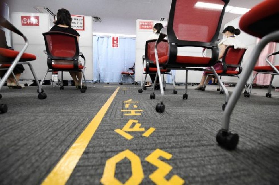 Miembros de la tripulación de cabina de Japan Airlines esperan para recibir la vacuna contra el coronavirus.