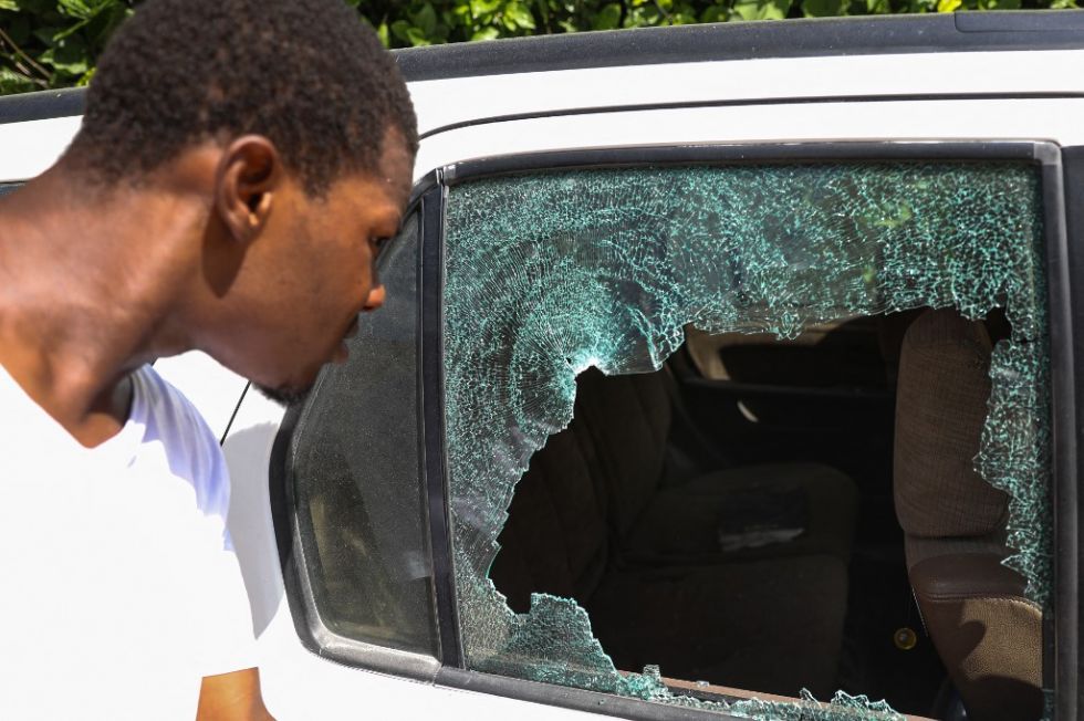 Un hombre mira los agujeros de bala en un automóvil fuera de la residencia presidencial en Puerto Príncipe, Haití.