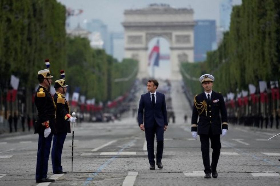 Emmanuel Macron pasa revista ante efectivos militares en la avenida de Los Campos Elíseos con el Arco de Triunfo al fondo, hoy en París.