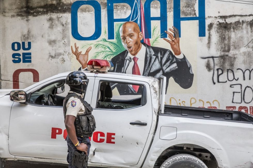 Un policía espera frente a un mural del fallecido presidente haitiano Jovenel Moise en Puerto Príncipe.