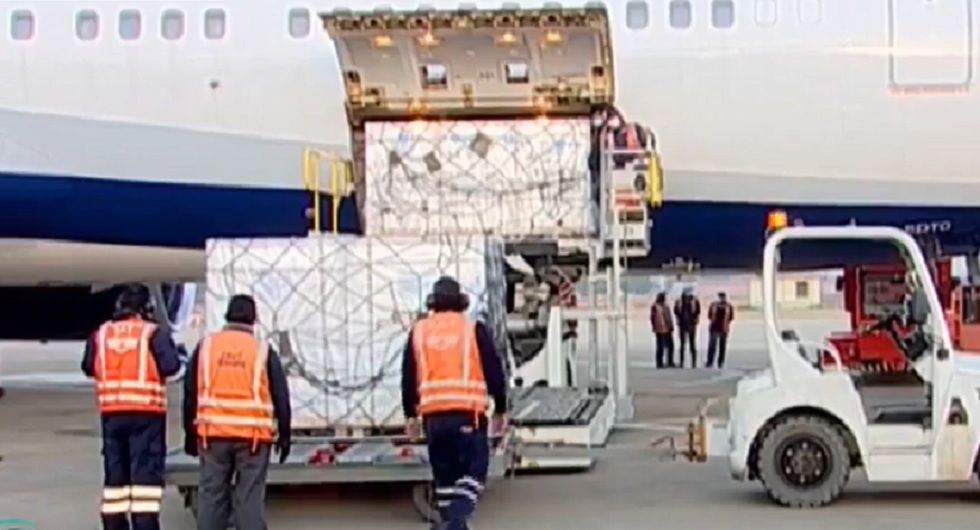 Personal aeropuertario descarga los contenedores con dosis de la vacuna Sinopharm.