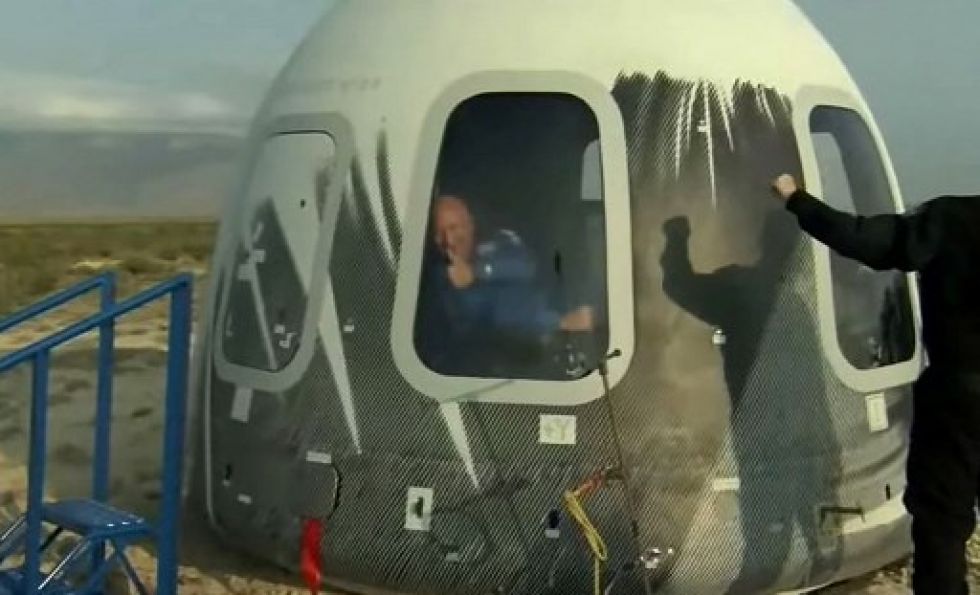 Jeff Bezos saluda desde la cápsula Blue Origin luego de aterrizar en un predio tras su vuelo inaugural.