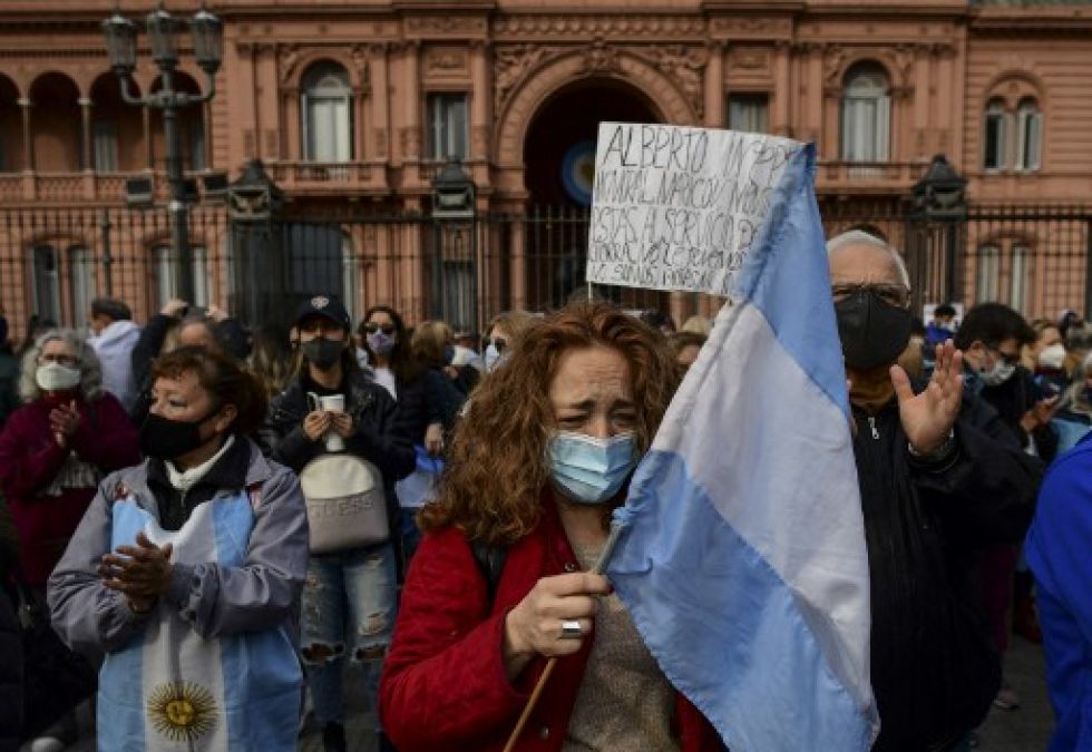 Una mujer sosteniendo una bandera argentina, grita frente a la Casa de Gobierno de la Casa Rosada durante la “Marcha de las Piedras” en homenaje a las víctimas del covid-19.