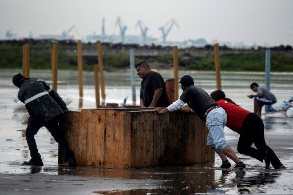 Trabajadores retiran muebles de la playa cuando las fuertes olas llegan a la costa debido al huracán Grace, que alcanzó la categoría 2, en Boca del Río, Veracruz.