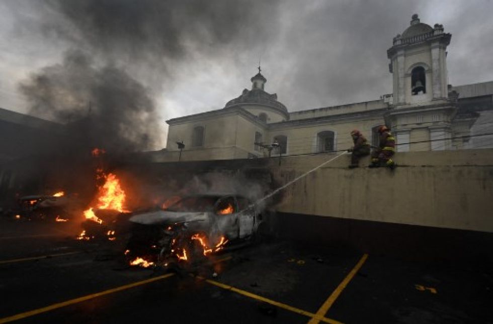 Bomberos intentan sofocar el fuego provocado por los disturbios en la sede del Congreso de Guatemala.