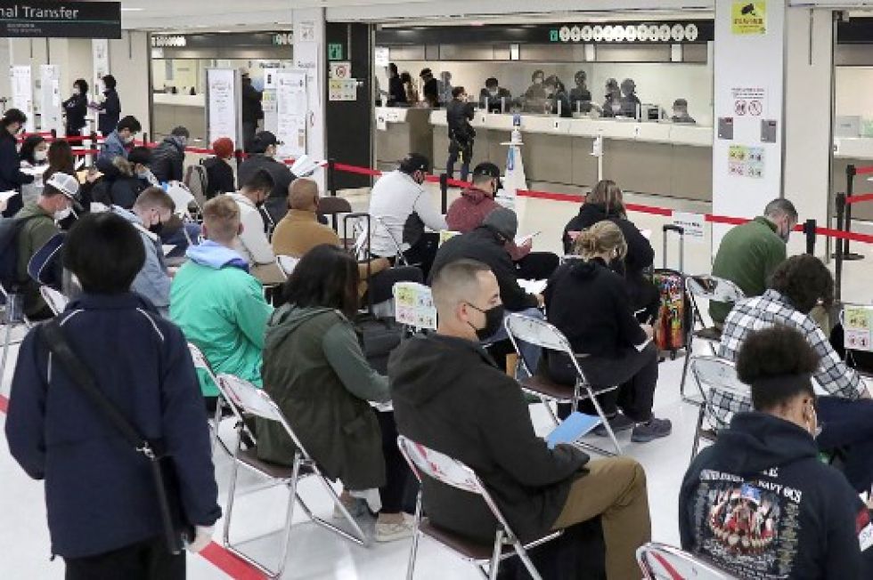 Las personas esperan ser transportadas a una instalación de cuarentena después de llegar al aeropuerto de Narita en Narita, prefectura de Chiba el 29 de noviembre de 2021.