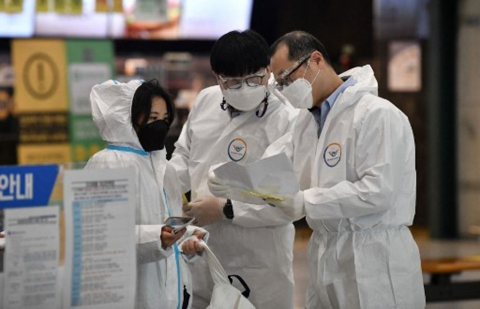 Miembros del personal guían a un viajero (i) en la sala de llegadas del Aeropuerto Internacional de Incheon, en medio de la preocupación por la variante Ómicron.
