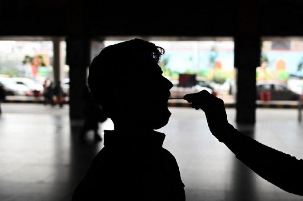 Un trabajador de la salud recolecta muestras de hisopos de un viajero para detectar el coronavirus Covid-19 en una estación de tren en Nueva Delhi.