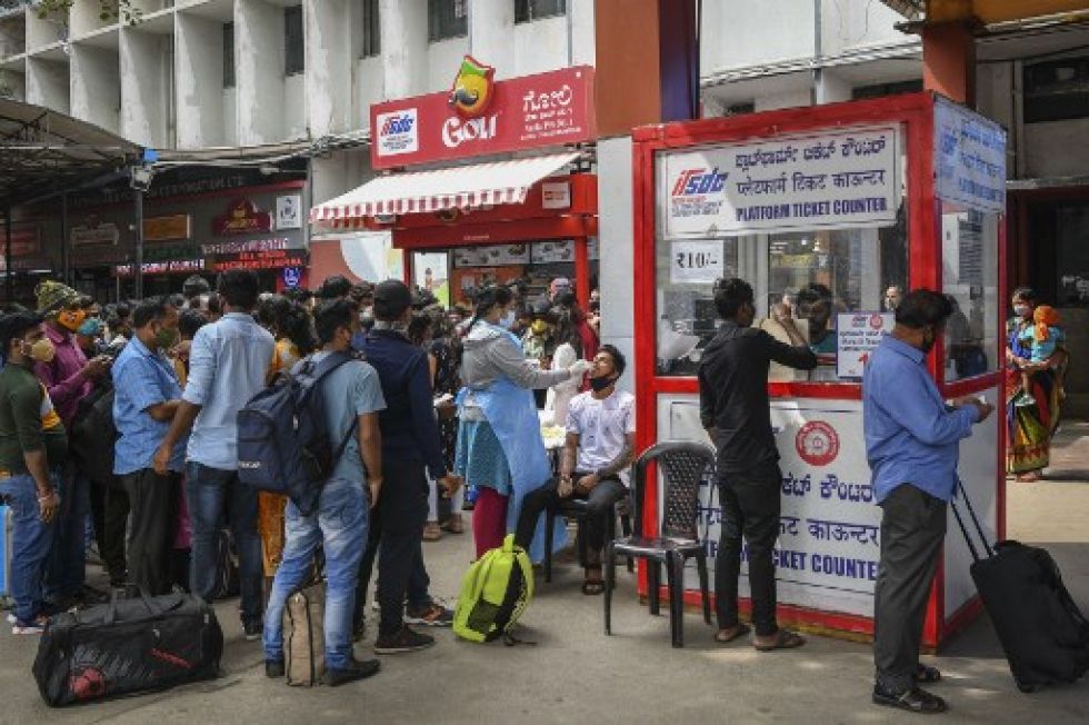 Funcionarios de salud realizan una prueba de detección del coronavirus covid-19 de un pasajero en una estación de tren durante una campaña de control en Bangalore, India.