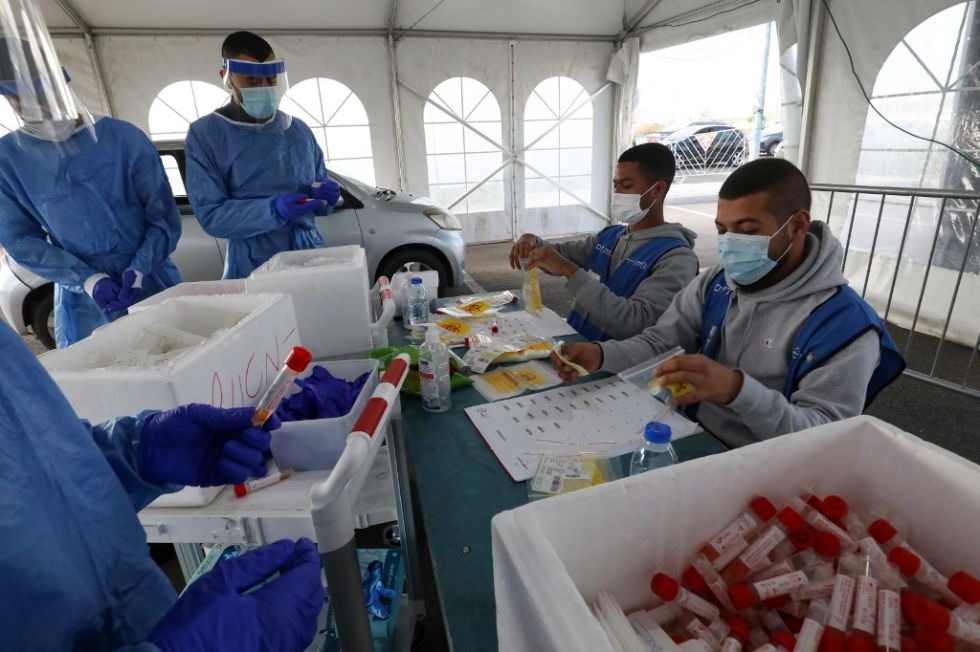 Personal médico manipula muestras para coronavirus en un punto de testeo masivo en Israel.
