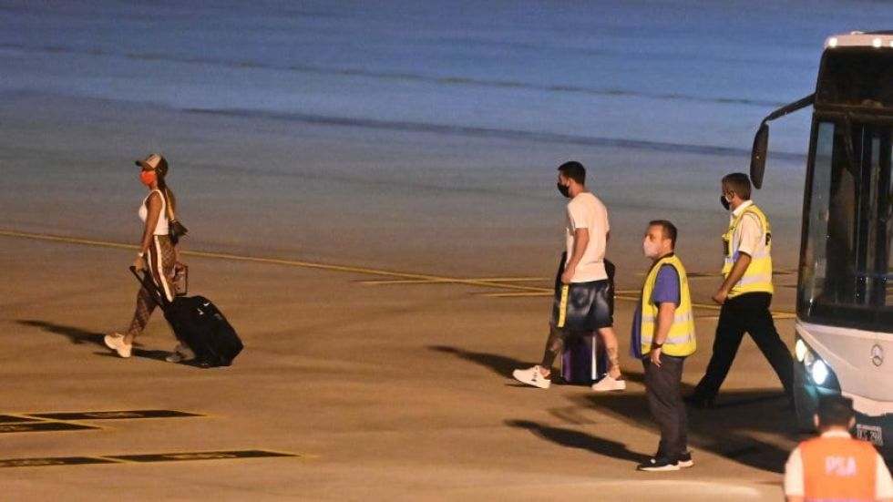 Lionel Messi (d) camina rumbo a su avión privado detrás de su esposa Antonella Roccuzzo.