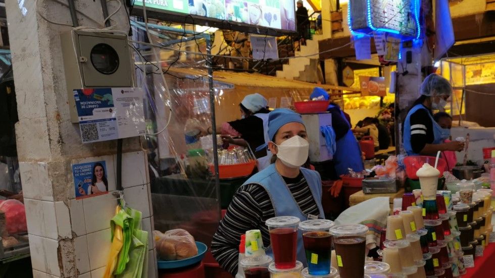 Las vendedoras del mercado Central exhiben su carnet de vacunación.