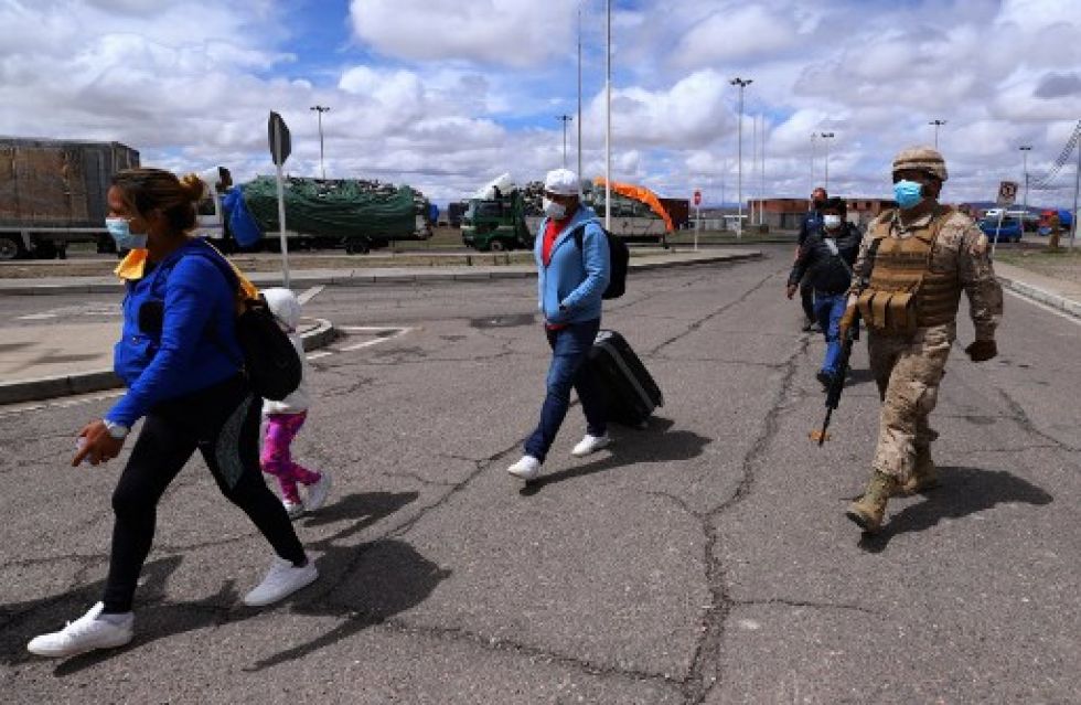 Un efectivo militar chileno acompaña a un grupo de inmigrantes en el paso de Colchane, en la frontera con Bolivia.