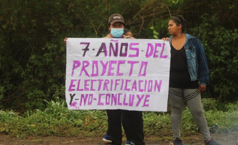 Un comunario de Isipotindi muestra un cartel de protesta en el bloqueo del lunes.