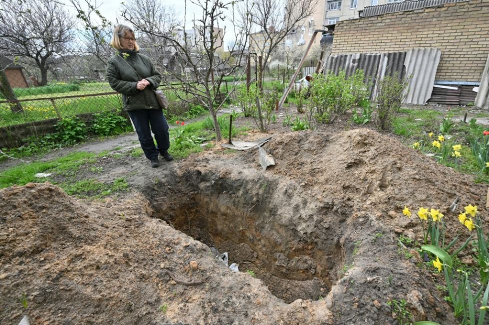 Lyudmyla Kizilova, de 67 años, junto a la tumba de su difunto esposo Valerii Kizilov, de 70, frente a su casa en Bucha, de donde se exhumó el cuerpo.
