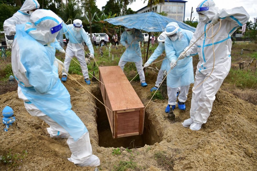 Unos hombres sepultan a una persona que falleció por covid-19 en Tailandia.