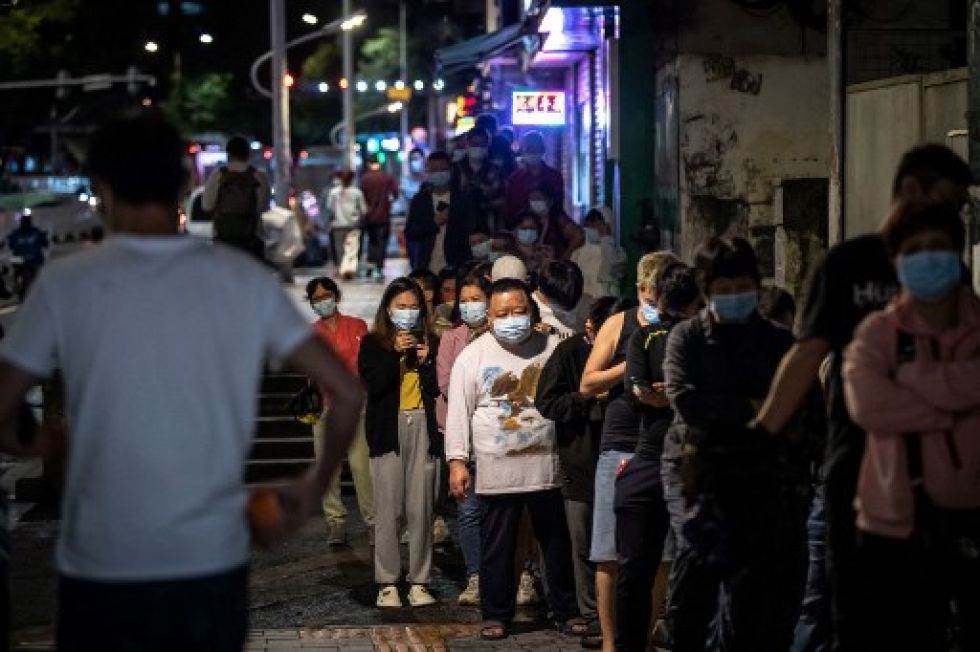 Residentes de Pekín forman filas ante un centro de diagnóstico de covid-19, en medio de una creciente ola de contagios.