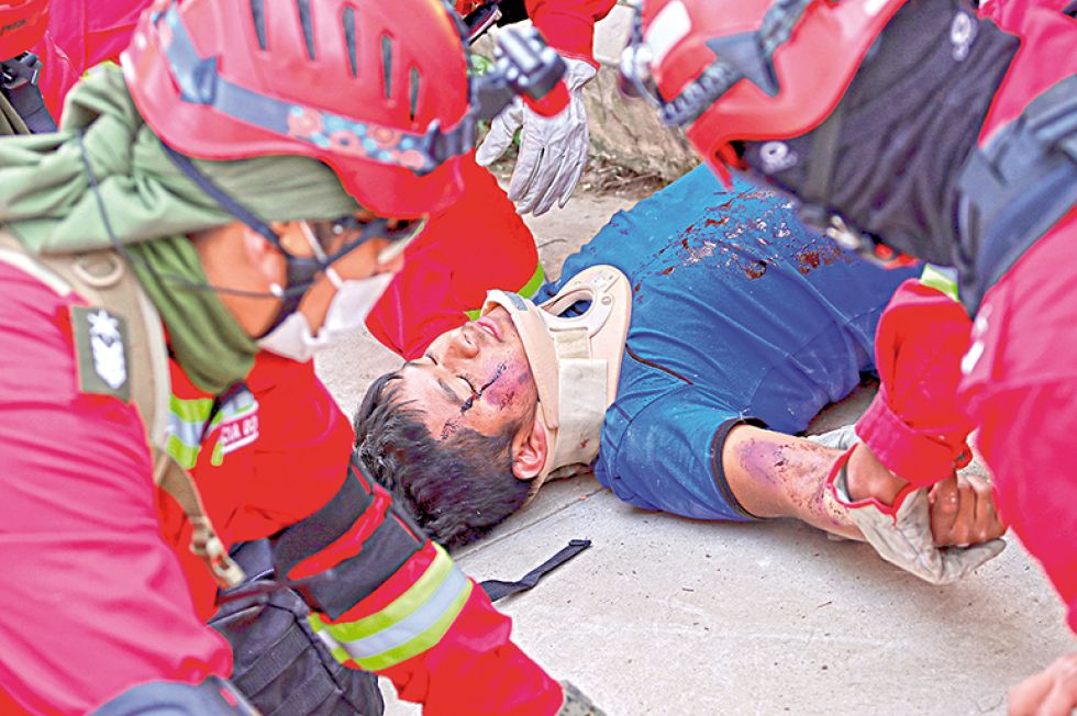 ENSAYO. Un estudiante afectado por el sismo es socorrido por las brigadas de rescate.