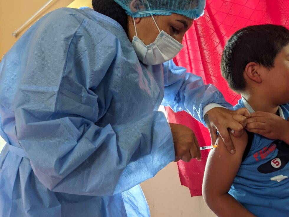 Una trabajadora de salud administra una dosis de la vacuna anticovid a un niño.