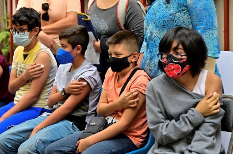 Niños mexicanos hacen fila después de recibir su vacuna contra el covid-19. Los casos vuelven a subir en América Latina, según un reporte regional.