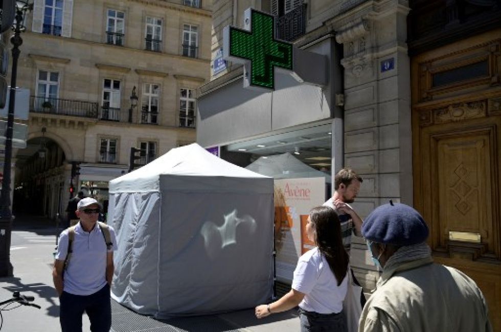 Transeúntes pasan cerca de un centro de vigilancia sanitaria en una calle de París, Francia, que vive una fuerte ola de calor en esta temporada.
