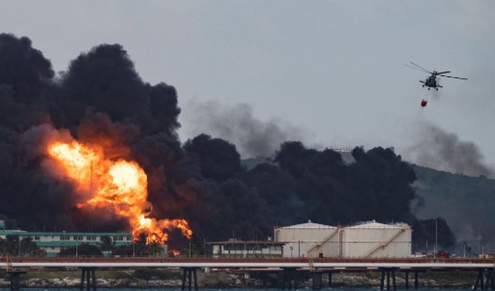 Un helicóptero de bomberos arroja agua sobre un incendio masivo en un depósito de combustible en Matanzas, Cuba, este lunes.
