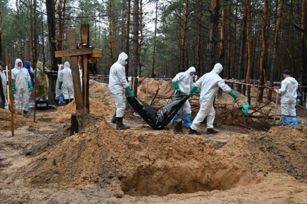 Investigadores llevan una bolsa con un cadáver en un bosque cerca de Izium.