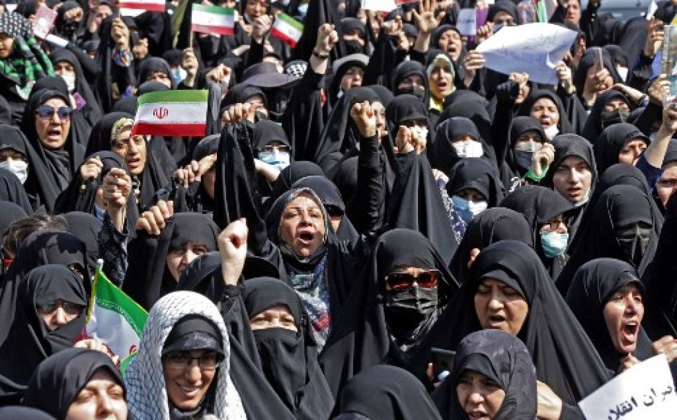 Iraníes ondean la bandera nacional mientras marchan durante una manifestación a favor del hiyab en la capital, Teherán.