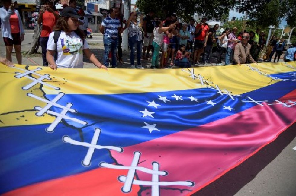 La gente muestra una pancarta que muestra las banderas colombiana y venezolana cosidas entre sí.