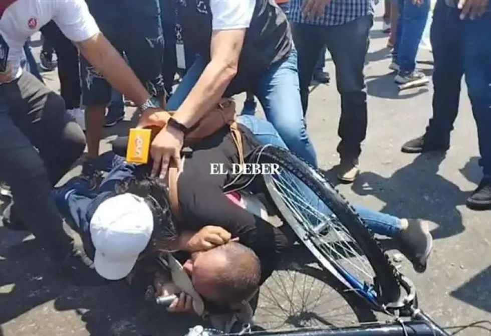 Una mujer protege con su cuerpo al periodista de Unitel, Yerko Guevara, que era golpeado por grupos afines al partido gobernante.