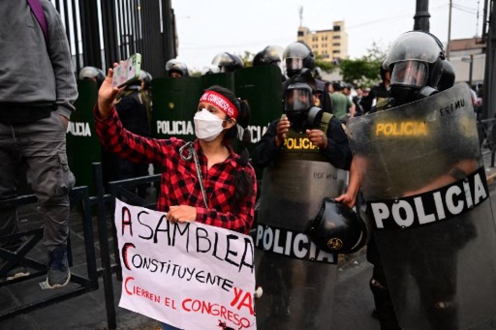 Una seguidora de Pedro Castillo junto a la Policía antidisturbios durante una protesta para exigir el cierre del Congreso y la liberación del expresidente, este jueves.