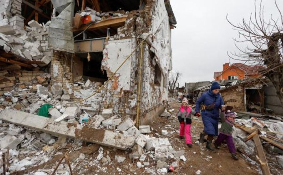 Una mujer camina con sus hijos a través de la destrucción provocada por un ataque aéreo ruso en Hlevakha, a las afueras de Kiev