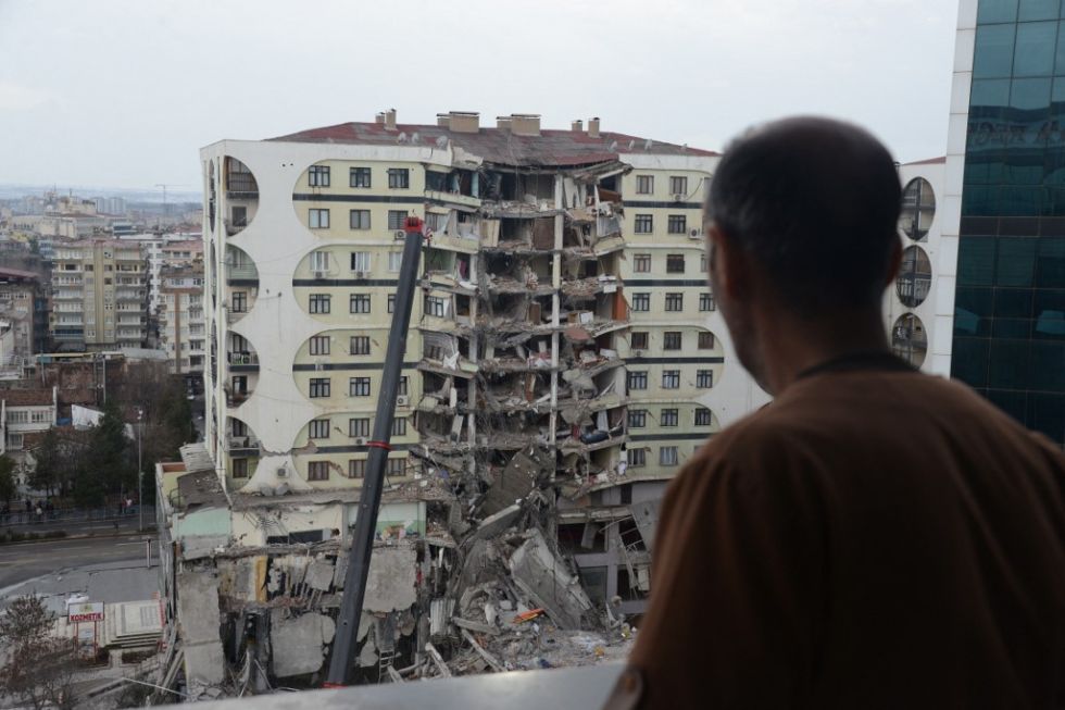 Un hombre observa las operaciones de búsqueda y rescate realizadas entre los escombros de un edificio derrumbado, en Diyarbakir, al sureste de Turquía.