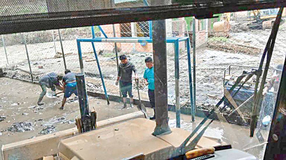 EMERGENCIA. Vecinos de la población de Yanacachi limpian el lodo que dejó en una cancha multifuncional el desborde del río por las lluvias.