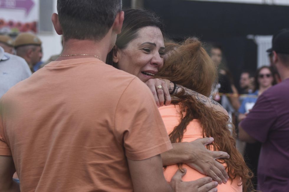 Familiares se abrazan a la entrada de la guardería Cantinho Bom Pastor (Brasil), donde fueron asesinados varios niños con arma blanca