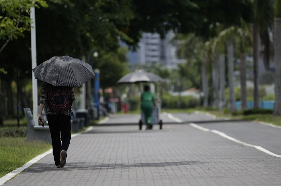 Vendedores se protegen del sol con sombrillas en la zona costera, hoy en Ciudad de Panamá (Panamá).