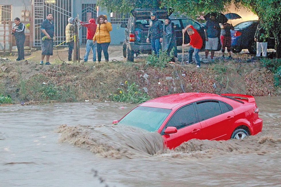 TRAGEDIA. Fotografía tomada este domingo en la que se observa un auto cubierto de agua en una calle de Baja California (México).
