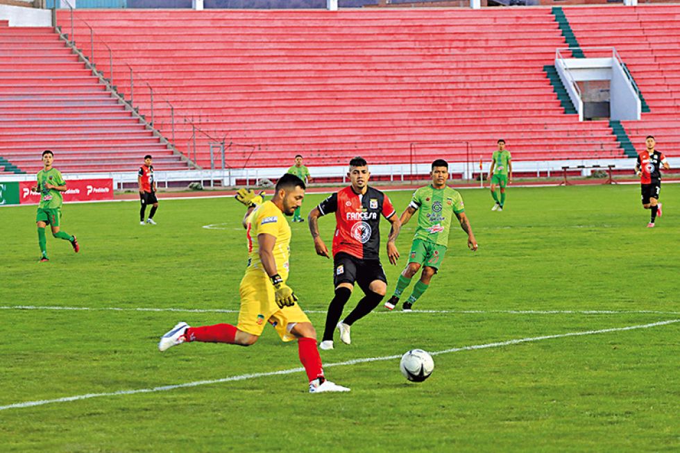 El arquero cruceño Junior Peña se alista para despejar un balón ante la presión del delantero cementero Kevin Nieto.