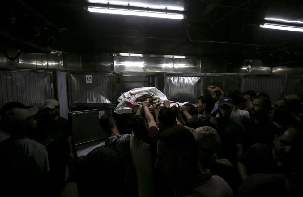 Los palestinos cargan el cuerpo de un combatiente muerto durante el asalto a los asentamientos israelíes por parte de militantes de la milicia Ezz Al-Din Al Qassam.