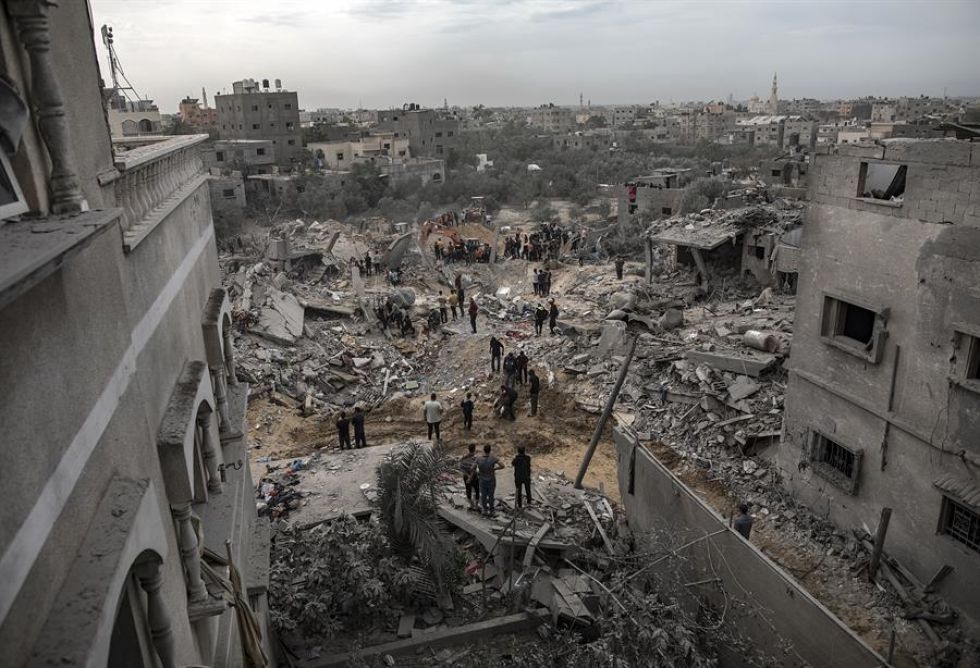 Palestinos buscan cadáveres y supervivientes entre los escombros de un edificio residencial tras un ataque israelí en Jan Yunis.