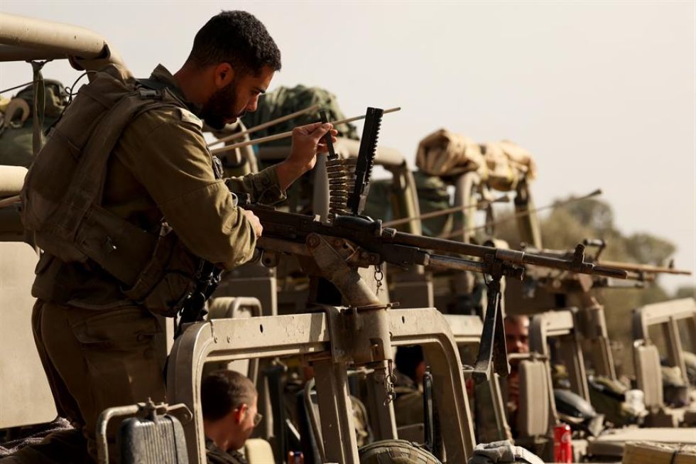 Un soldado israelí realiza trabajos de mantenimiento de su arma en un punto de reunión a lo largo de la frontera con Gaza.