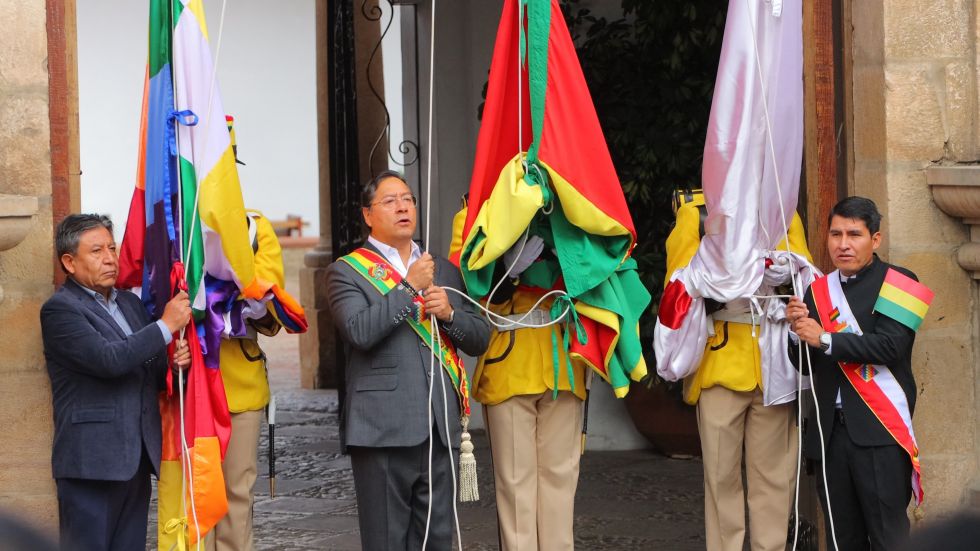 El presidente Luis Arce (c) iza la bandera boliviana junto a David Choquehuanca (i) y Damián Condori (d).