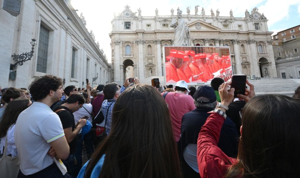 Los fieles observan una pantalla gigante que muestra imágenes de la procesión de cardenales a la Capilla Sixtina.