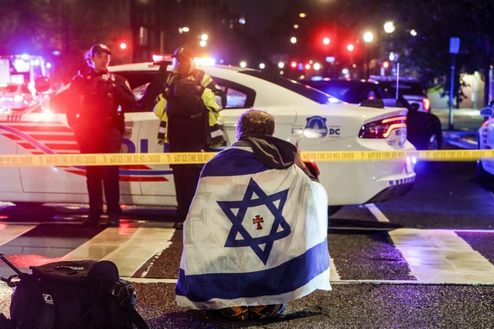 Un hombre con una bandera israelí sobre los hombros cerca del lugar donde dos personas fueron asesinadas a tiros.