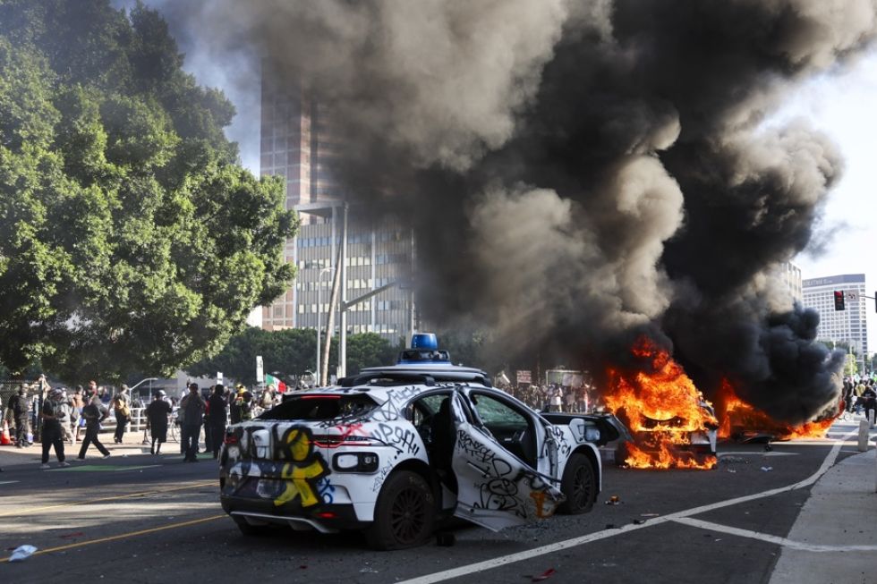 Vehículos vandalizados arden durante las protestas provocadas por las redadas migratorias en Los Ángeles.