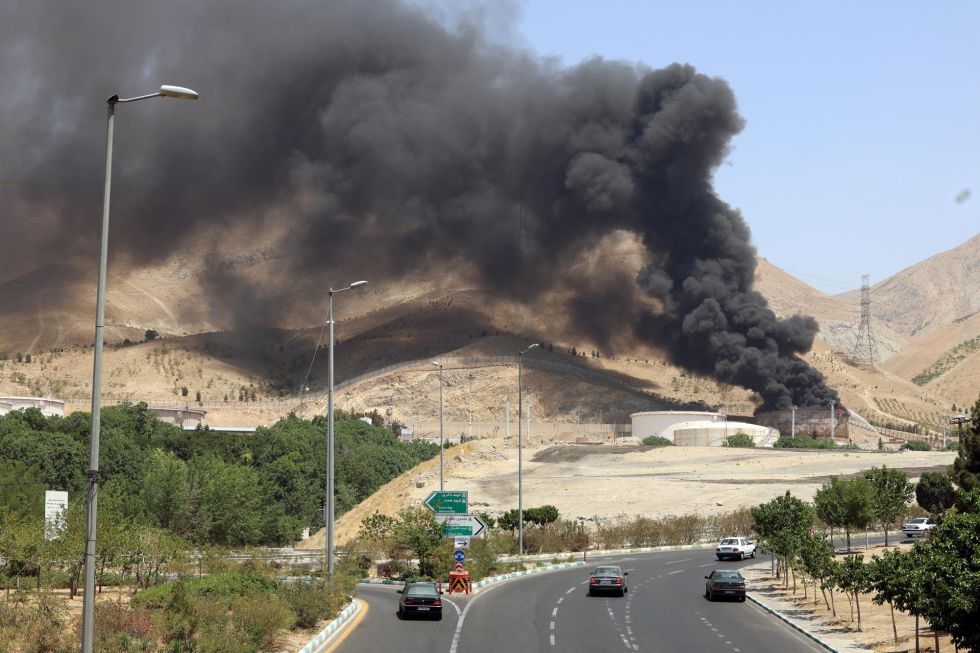 Vehículos circulan por una autopista mientras se eleva humo al fondo desde una refinería de petróleo, al noroeste de Teherán