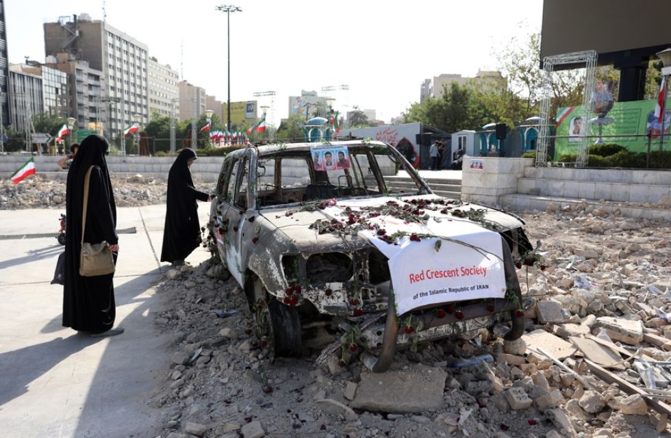 Mujeres iraníes con velo junto a una ambulancia destruida en un ataque israelí, en Teherán, Irán.